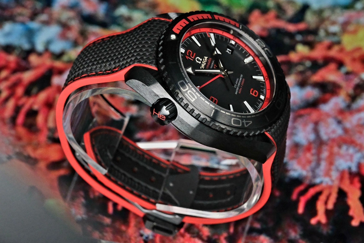 OMEGA Seamaster Planet Ocean 600M Deep Black GMT 215.92.46.22.01.003 — coiled on black and red rubber strap